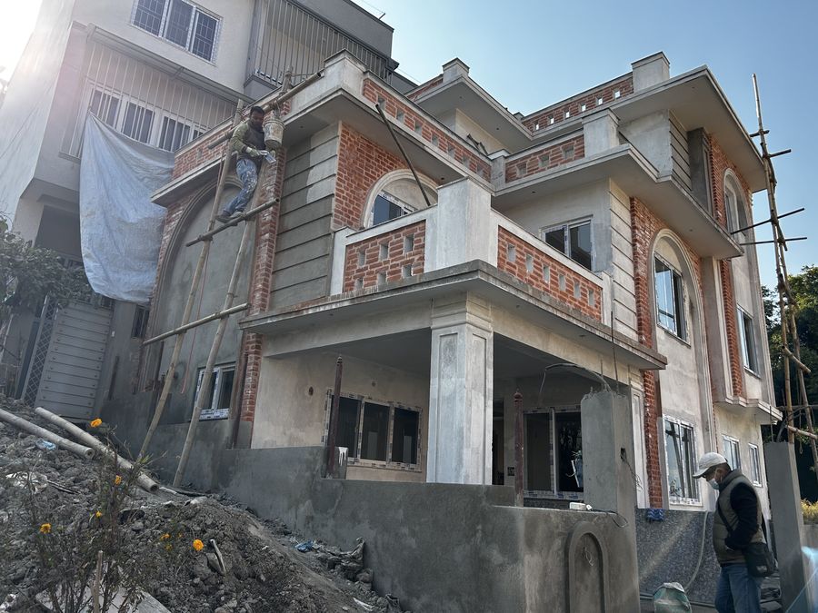 The same three-storey house on scaffold, brick panels and arch complete, render and finishes still to come