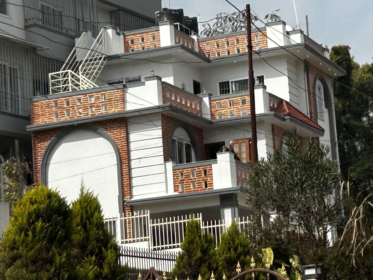 Completed three-storey house with exposed-brick panels, a tall arched window over the entrance and a white boundary fence