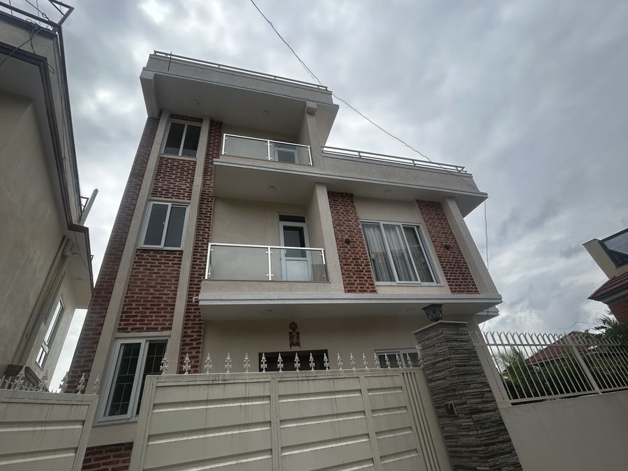 Front of Bidhya Bhattarai House, a completed three-storey house in white render with red-brick panels and glass-balustraded balconies