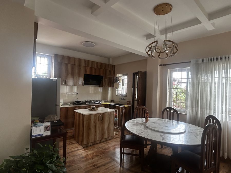 Kitchen and dining room with timber-fronted cabinets, an island and a round marble dining table under a ring pendant