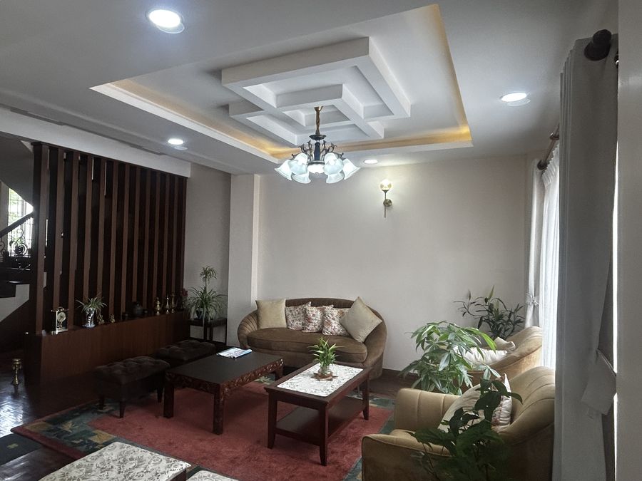 Living room with a timber slat screen, a coffered ceiling with cove lighting, a red rug and cane armchairs