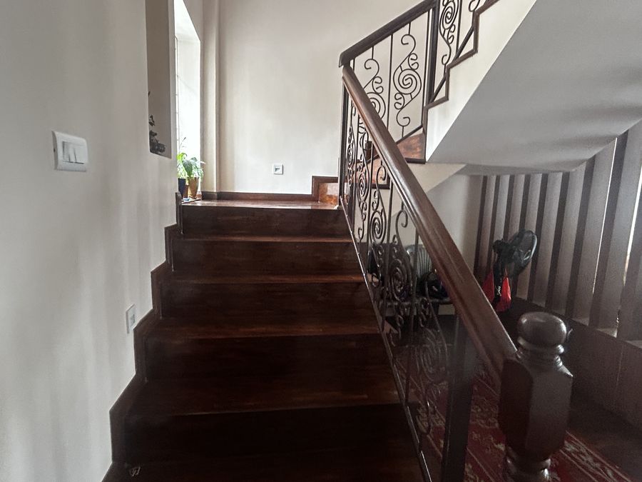 Timber staircase with a dark wrought-iron balustrade and a turned newel post