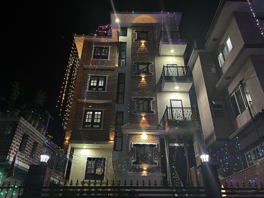 Maharjan House, an exposed-brick house, at night with festival lights strung down the facade and lit balconies